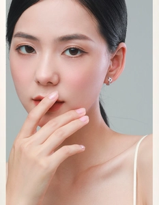 Elegant silver hoop earrings with clear round stones worn by a model on light background