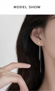 Detail of elegant silver butterfly tassel earrings with long chains on model