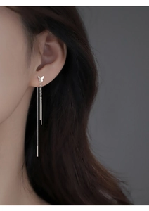 Macro view of S925 silver butterfly tassel drop earrings worn by a model