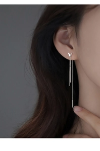Macro detail of elegant 925 silver butterfly tassel earrings on model with long chains