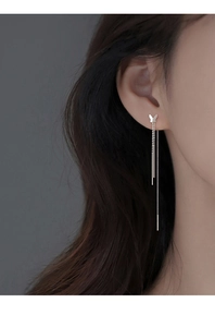 Close-up of silver-plated butterfly tassel earrings worn by a model in detail view