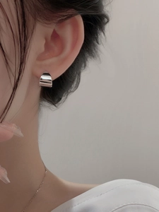 Close-up of minimalist silver geometric hoop earring shown on ear for actual scale