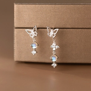 Macro shot of silver asymmetric butterfly earrings with iridescent moonstone drops