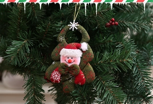 Close-up of a plush snowman ornament with red hat on a green Christmas tree hanger