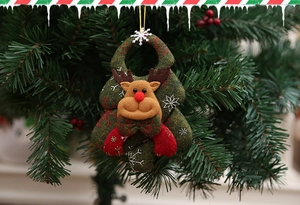 Detail of felt reindeer ornament with red bow hanging on Christmas tree branch