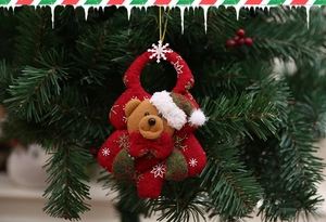 Detail of plush brown teddy bear Christmas tree ornament with festive red fabric and snowflakes