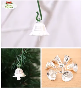 Silver Christmas bell ornaments with green hooks hanging on a festive pine tree branch