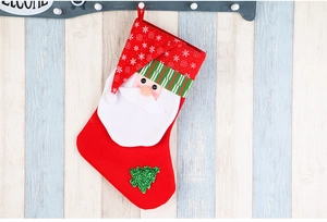 Detail of red Christmas stocking with Santa Claus applique and green glitter tree on wood