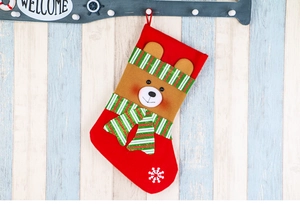 Detail of red Christmas stocking featuring 3D plush bear and white snowflake embroidery
