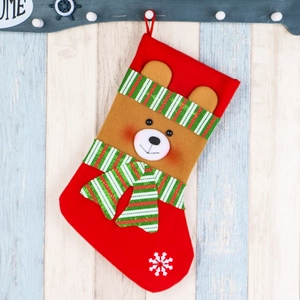 Christmas stocking with a 3D plush brown bear on a red fabric, hung on a rustic wooden wall