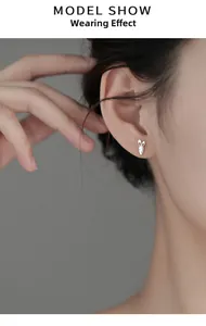 Close-up of cute S925 silver rabbit and carrot stud earrings worn on a model ear