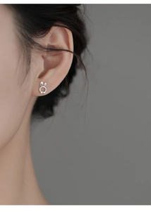 Macro detail of S925 sterling silver rabbit stud earring with bow accent on earlobe