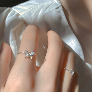 Detailed view of silver minimalist rings featuring a 3D iridescent butterfly and zircon