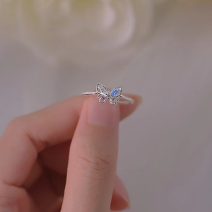 Three-dimensional silver butterfly ring with colorful zircons on a soft floral background