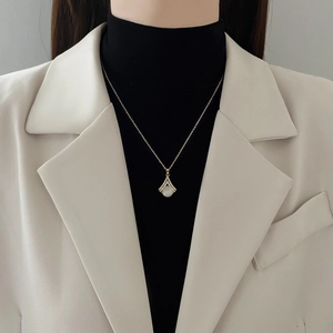 Goldene Fächer-Opal-Halskette mit Diamanten an Model trägt beigen Blazer und Rollkragen