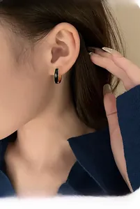 Close-up of minimalist U-shaped black enamel hoop earring with gold-plated trim on model