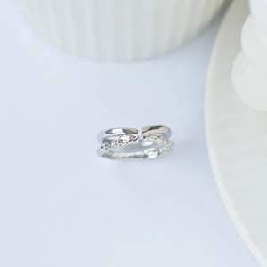 Vue macro d'une bague double couche argentée avec textures lisse et martelée sur fond bleu