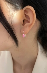 Detail of pink tulip earrings showing enamel petals and silver hooks on a model