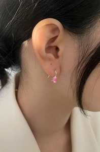 Detailed close-up of pink tulip drop earrings with silver hooks on female model