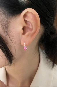Close-up of pink tulip drop earrings with silver trim worn by a model in a soft setting