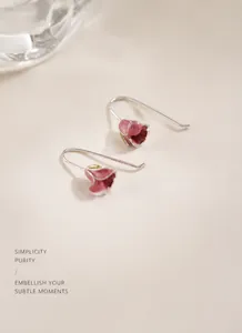 Macro shot of pink tulip flower earrings with silver hooks on textured fabric