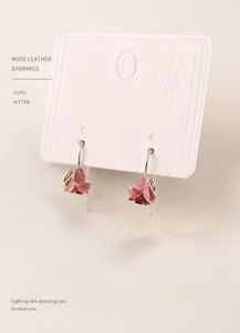 Detail of pink tulip drop earrings with green leaves on a white vintage jewelry card