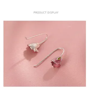 Detailed close-up of pink tulip enamel flower earrings with green leaf on silver hooks