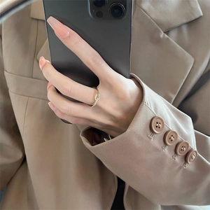 Detail of twisted gold ring with pavé diamond accents worn on hand with phone