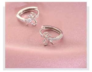 Vue macro de boucles d'oreilles nœud en argent S925 avec zircons sur satin rose