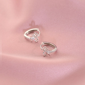 Boucles d'oreilles créoles nœud en argent S925 avec zircons sur fond de soie rose