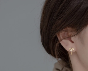 Élégantes boucles d'oreilles nœud dorées avec zircones portées par un mannequin chic