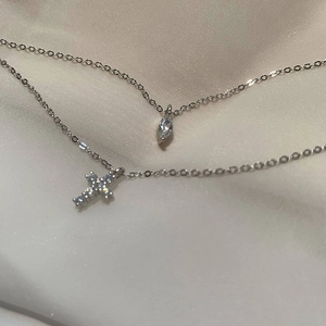 Close-up of S925 silver double layer cross necklace and marquise zircon on silk fabric