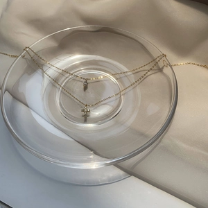 Close-up of gold double-layer necklace with zircon cross and teardrop pendant on satin