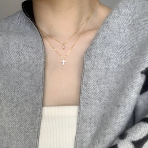 Close-up of double-layer gold necklace featuring a cross and water drop zircon pendant