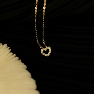 Makroaufnahme: Goldener hohler Herzanhänger mit Pavé-Diamanten an schicker Gliederkette