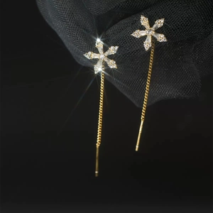 Close-up of elegant gold snowflake tassel earrings with zircon stones on black background