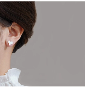 Detailed view of S925 silver heart earring with mother of pearl inlay on model ear