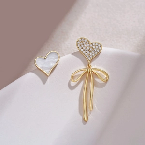 Detailed view of asymmetric S925 silver heart earrings with bow and mother of pearl inlay