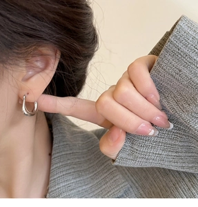 Gros plan d'une boucle d'oreille ovale argentée minimaliste portée sur un mannequin