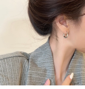 Gros plan de boucles d'oreilles créoles argentées minimalistes sur un mannequin