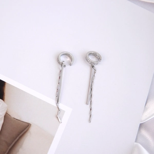 Detail von silbernen langen Quasten-Ohrklemmen mit Zirkonia-Mikroverzierung im minimalistischen Stil