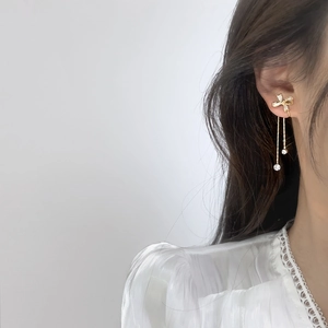 Detailansicht eleganter goldener Schleifenohrringe mit langen Quasten und Kristallen