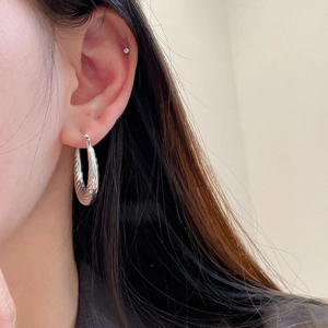 Macro detail of silver twisted hoop earring showing high-polished spiral metal texture