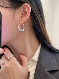 Detail of S925 sterling silver twisted hoop earrings on model for a modern fashion look