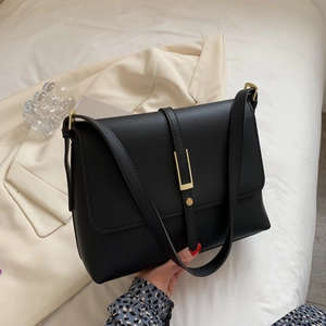 Minimalist black faux leather crossbody bag featuring a signature gold U-shaped buckle closure
