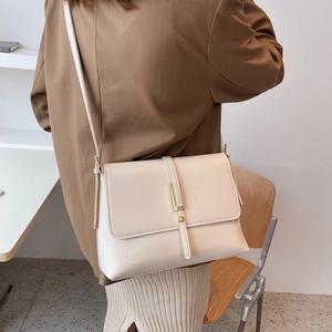 Detailed side view of an elegant beige crossbody bag styled with a brown blazer outfit