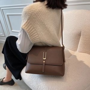 Close-up of a vintage dark brown leather shoulder bag with a gold U-shaped metal lock