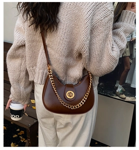 Detail of vintage half-moon bag with gold chain strap on a knit sweater backdrop