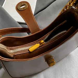 Detail showing high-quality golden hardware and zipper on a brown leather shoulder bag