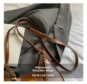 Dettaglio della borsa in pelle marrone vintage con tracolla regolabile e catena d'oro